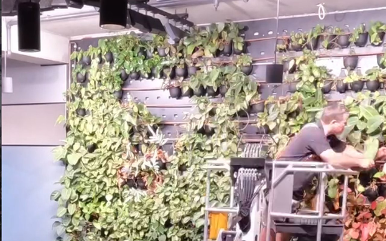 A Grolife technician on a cherry picker working on the modular planter and irrigation framework of a green wall
