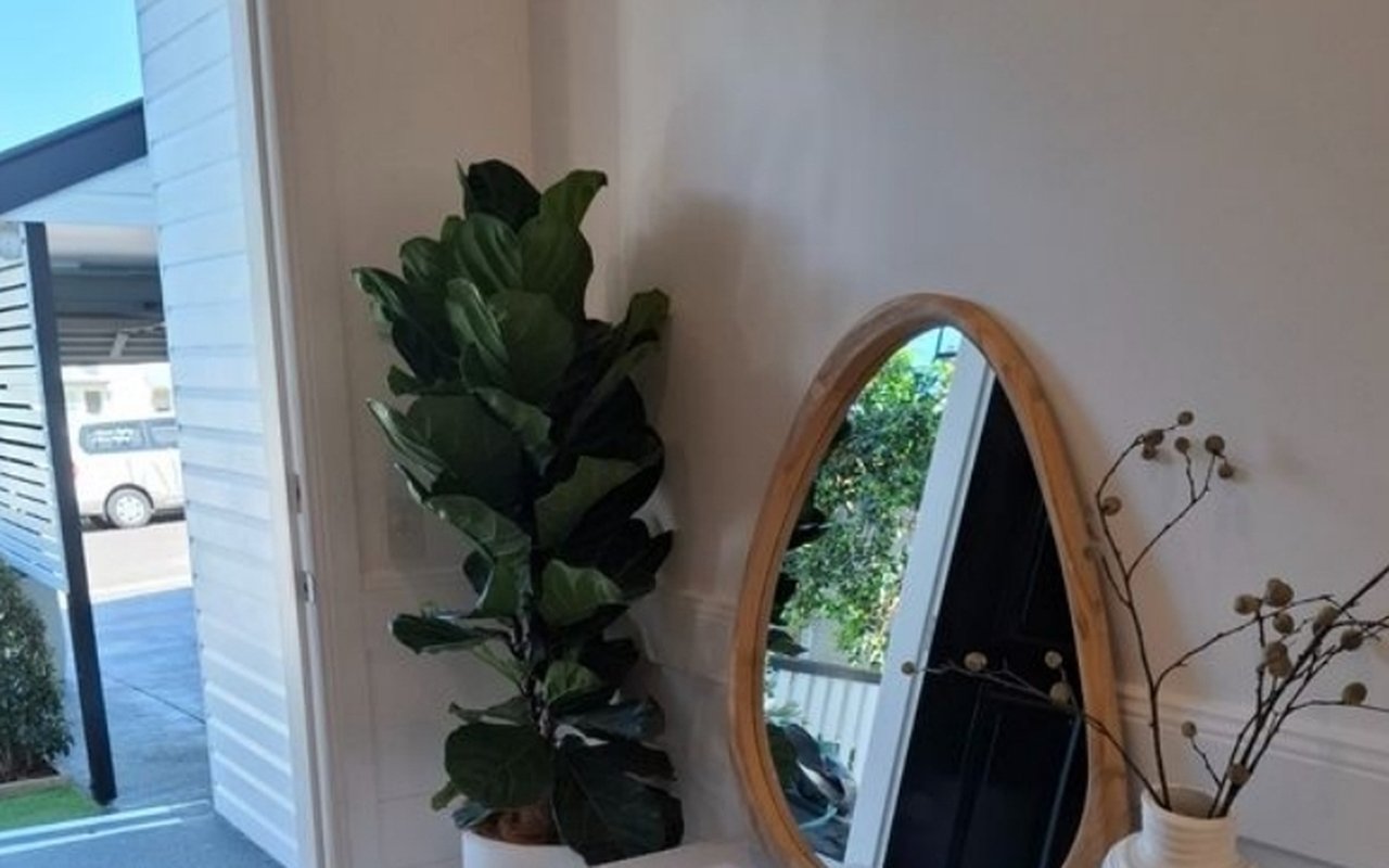 A styled entry vignette with a fiddle leaf fig in a white planter, fluted console, oval mirror and ceramic vase — the kind of detail revealed on a walk-through